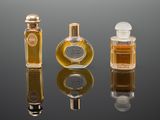 three bottles of perfume sitting next to each other on a reflective surface