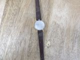 wrist watch on a wooden table with a leather strap