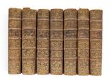 six vieux livres alignés sur une surface blanche