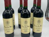 four bottles of red wine are lined up on a table