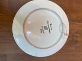 a white plate with a pink rim on a wooden table