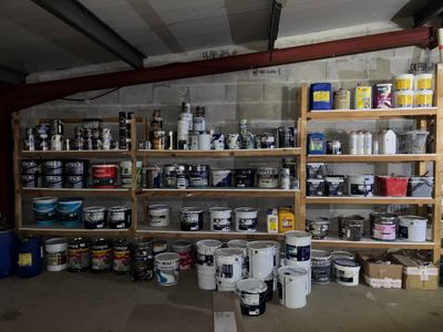 de nombreux pots de peinture et bidons sur les étagères du garage