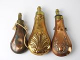 three antique brass pear shaped bottles are lined up on a white surface