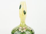 a green and yellow vase with flowers painted on it