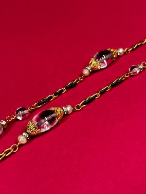 a close up of a pair of long necklaces on a red surface