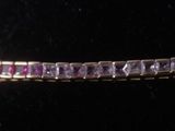 a close up of a bracelet with purple stones on a black surface