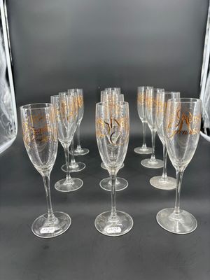 six verres à vin ornés de motifs dorés sont alignés sur une table
