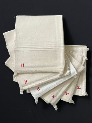 Plusieurs serviettes blanches ornées de lettres rouges sont empilées les unes sur les autres