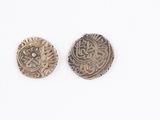 two silver coins on a white surface with a white background