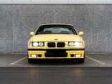 a yellow car parked in front of a gray wall