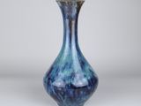a blue vase sitting on top of a table next to a white wall