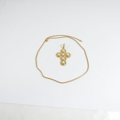un collier en or orné d'une croix, posé sur une feuille de papier