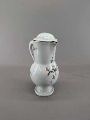 un petit vase blanc muni d'un couvercle, posé sur une table