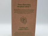 a box with a plant inside of it on a white surface