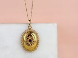 a close up of a gold locke necklace on a marble surface
