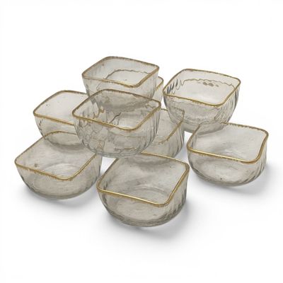 six clear glass bowls with gold rims on a white surface