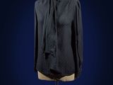 black shirt on a mannequin stand against a dark blue background