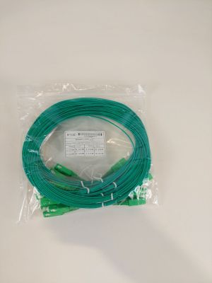 un gros plan d'un câble vert enveloppé de plastique posé sur une surface blanche
