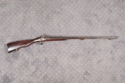 Un vieux fusil est posé par terre à côté d'un bâton.