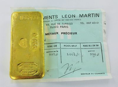 un lingot d'or jaune posé sur une feuille de papier, à côté d'un reçu