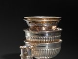 a group of silver dishes and cups sitting on top of a table
