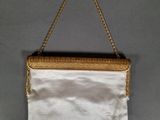 a white purse hanging on a wall with a gold chain