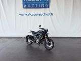 une moto garée devant une grande banderole blanche sur laquelle figure un logo