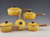 several yellow pots and pans with wooden handles on a table