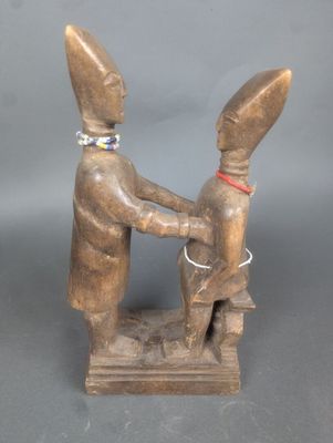 une image représentant une statue en bois de deux personnes se serrant la main