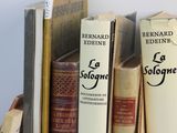 several old books are stacked on top of each other on a shelf