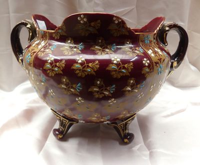 un vase rouge orné de fleurs dorées et bleues