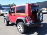 a red jeep parked in a parking lot with other cars in the background