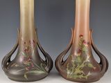 pair of vases with floral designs on them sitting on a table