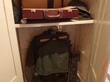 a closet with several suitcases and a guitar in it