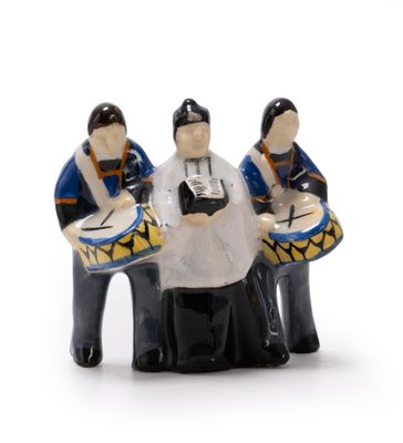 trois figurines représentant des personnes jouant du tambour sur une surface blanche