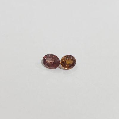 a pair of pink and yellow sapphires on a white surface