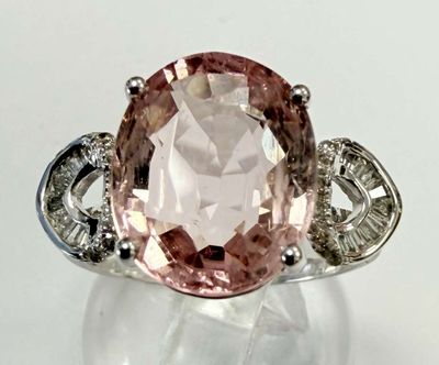 une photo d'une bague sertie d'un diamant rose et blanc posée sur une surface blanche