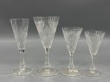 four clear wine glasses sitting on top of a white table