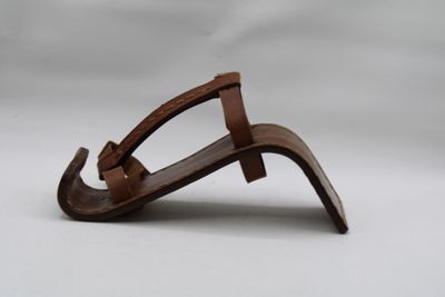 des sandales en cuir marron posées sur une surface blanche, avec un fond blanc