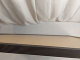a wooden shelf that has a white curtain behind it