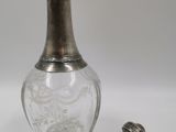 une bouteille en verre ancienne, munie d'un couvercle en argent et d'un petit bouchon en métal