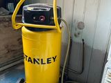un compresseur d'air Stanley jaune posé sur un chariot dans une pièce