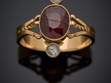 une bague en or sertie d'une pierre rouge et de deux diamants blancs