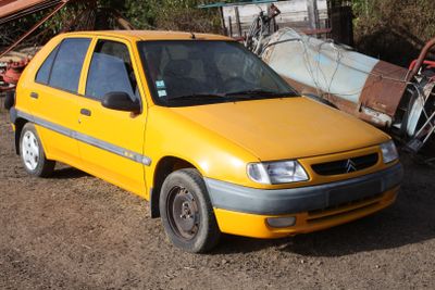 a yellow car that is parked next to a pile of junk