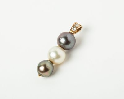 a close up of a pearl and diamond pendant on a white surface