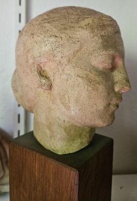 une sculpture représentant une tête, posée sur un socle en bois