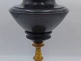 une urne ancienne noire et dorée surmontée d'un oiseau