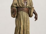 bronze statue of a man with a hat and robe on a wooden table