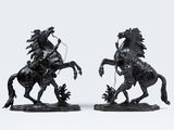 une paire de statues noires représentant un homme à cheval et une femme à cheval