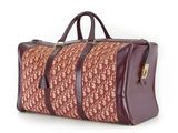 un sac de voyage marron et rouge posé sur une surface blanche